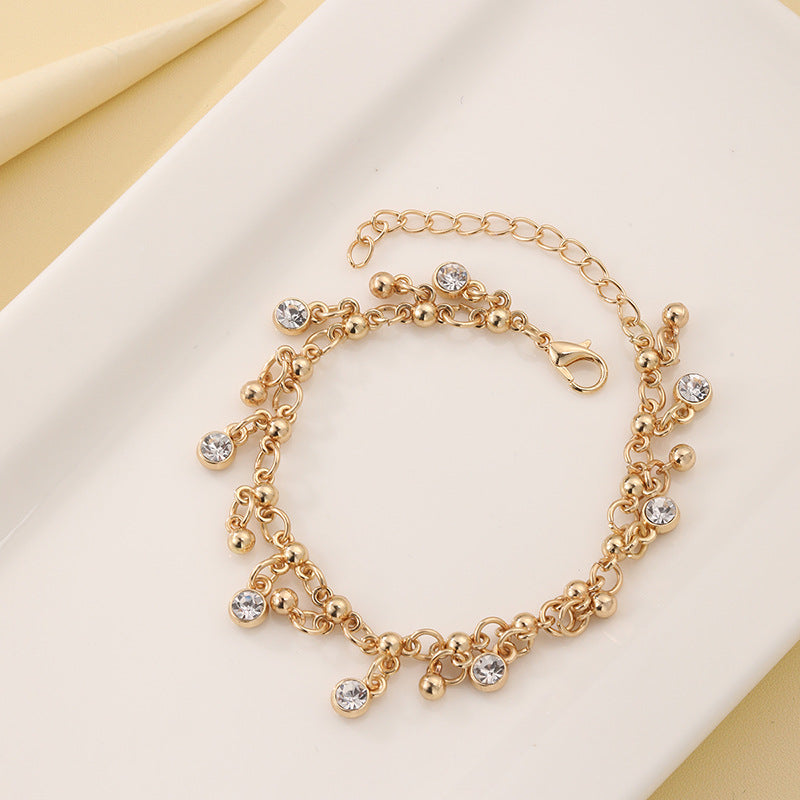 Gold tassel bracelet with diamond detailing close-up